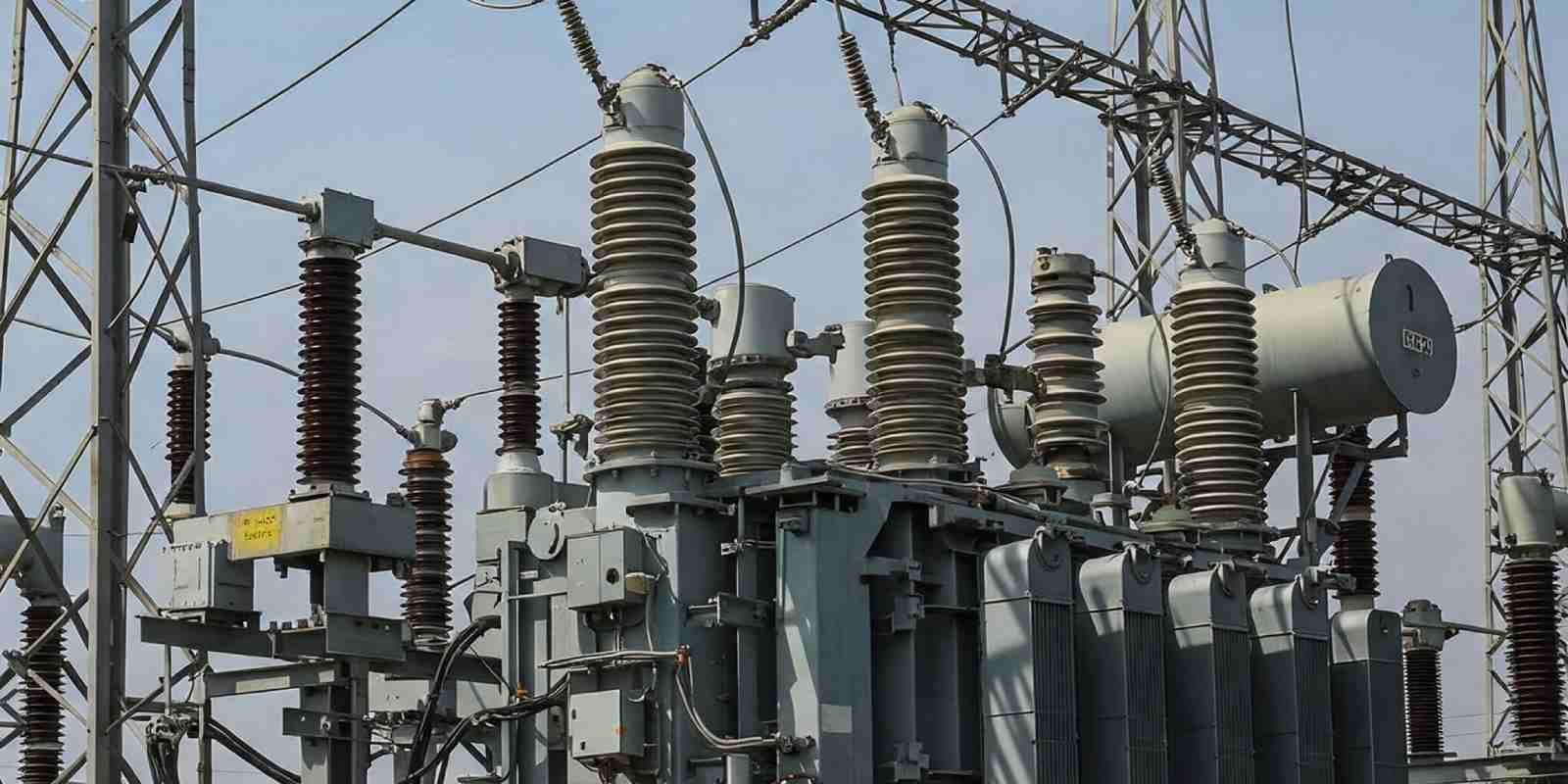 High voltage transformer and electrical insulators at an outdoor substation.